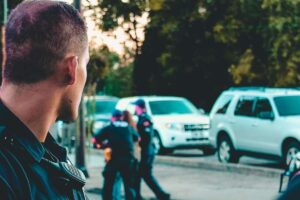 Agenti della polizia che arrestano un uomo in strada, con un poliziotto voltato in primo piano