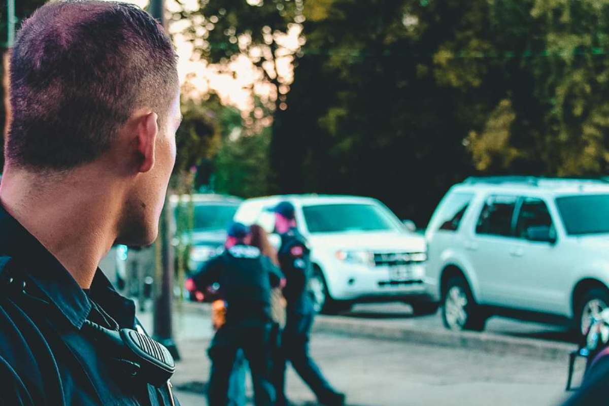 jene-stephaniuk-lkmGeyLItrw-unsplash-ls Agenti della polizia che arrestano un uomo in strada, con un poliziotto voltato in primo piano