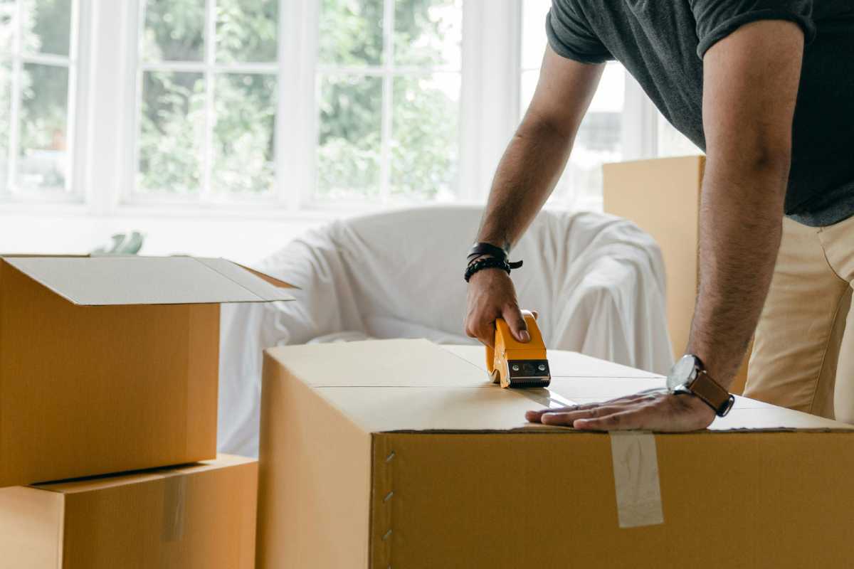 Un inquilino che chiude un pacco con del nastro adesivo